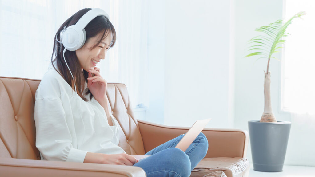 動画編集されたビデオをPCとヘッドホンで楽しむ女性