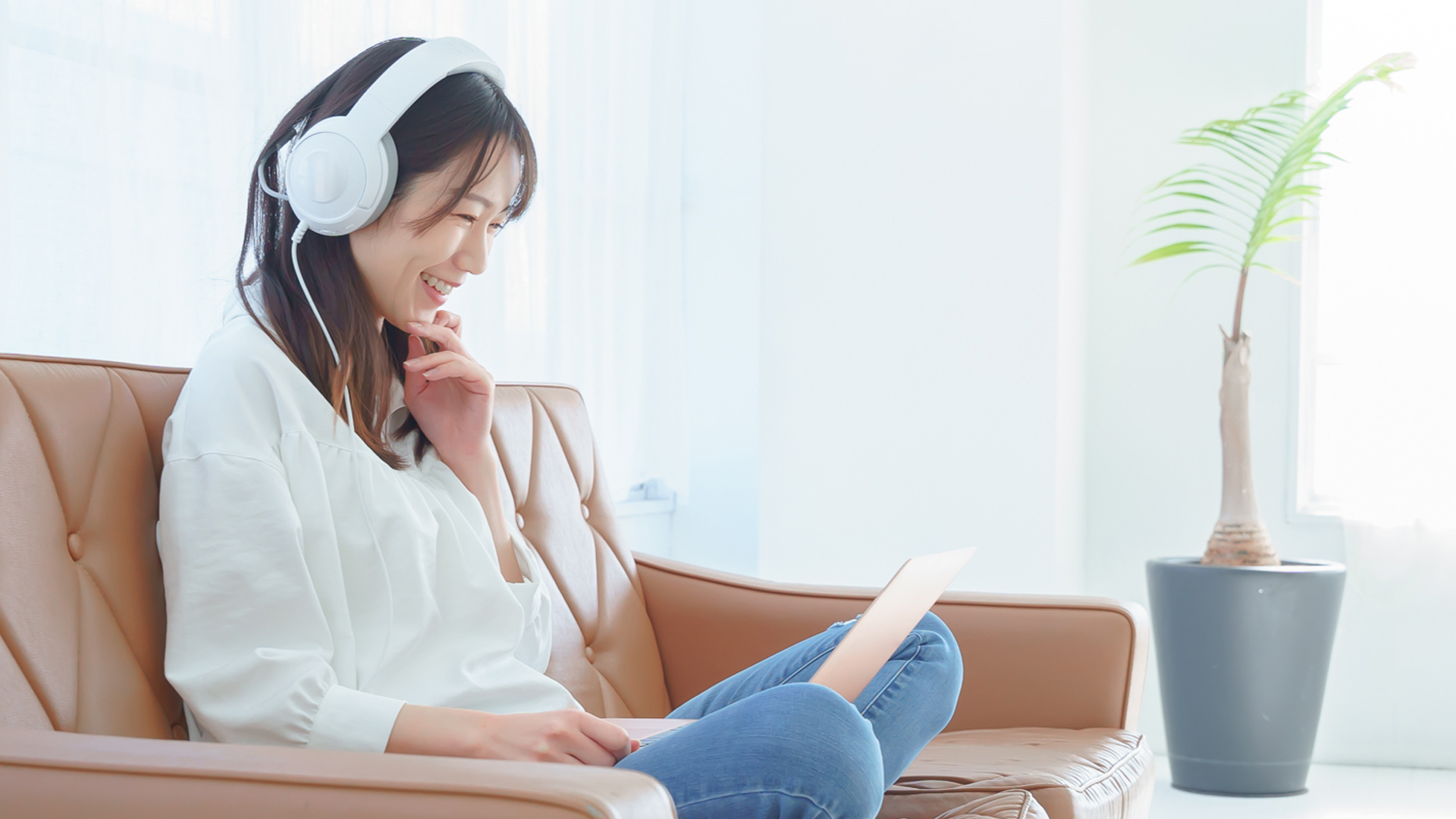 動画編集されたビデオをPCとヘッドホンで楽しむ女性